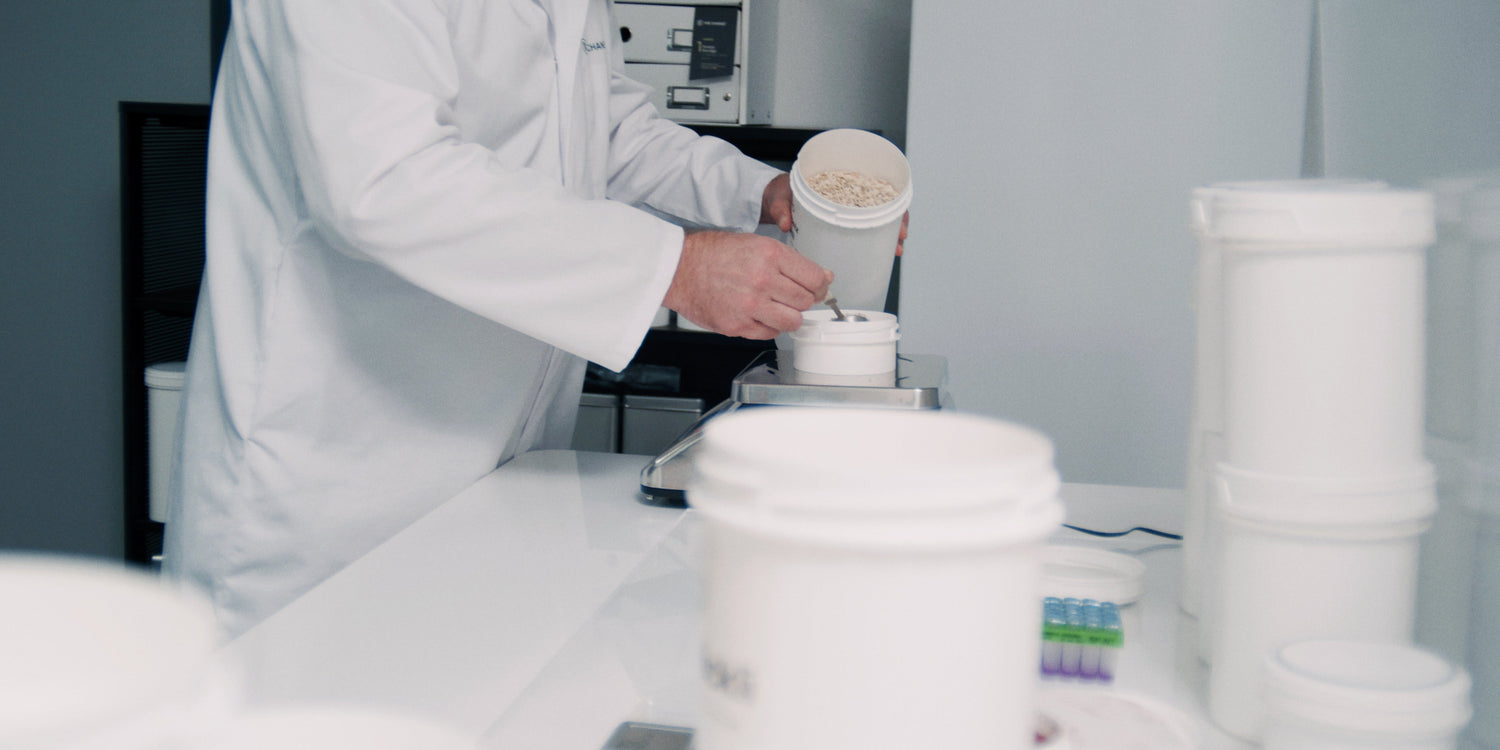 White lab coat professional weighing light-colored powder in a laboratory setting with sleek, modern equipment.