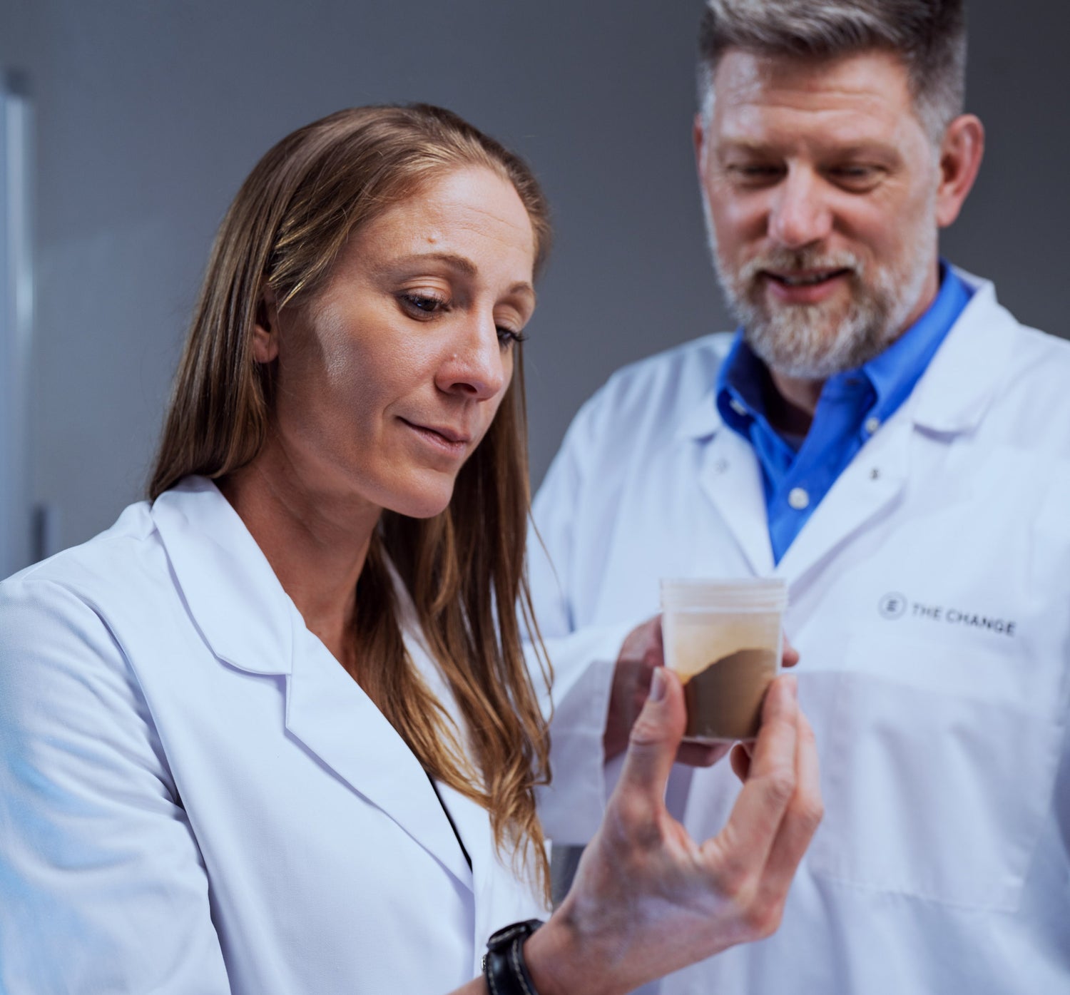 Researchers in lab coats examining a sample in a clear container, showcasing innovation in material testing.