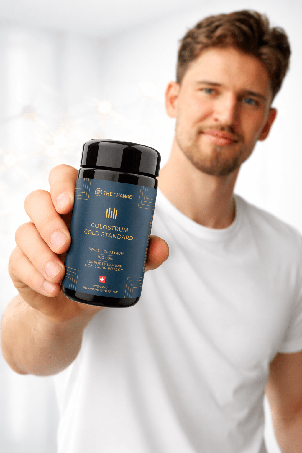 Black and gold colostrum supplement bottle held by a man in a white shirt, highlighting premium quality and Swiss origin.