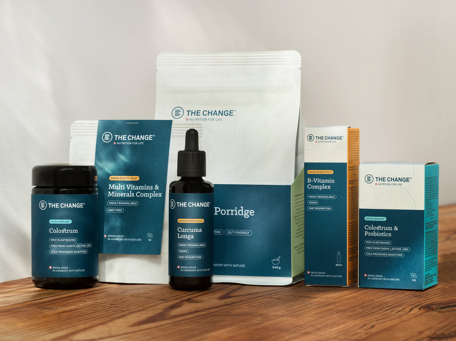Blue and white wellness products: colostrum, curcumin, vitamins, and porridge in eco-friendly packaging on wood surface.